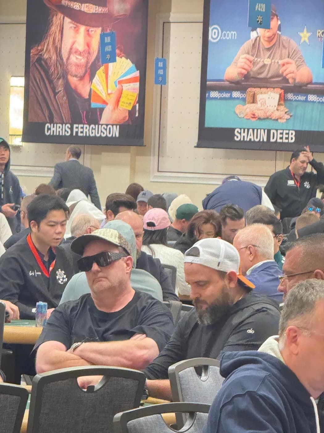 Joe.Pok3r en su mesa bajo los estandartes de campeones de Chris Ferguson y Shaun Deeb