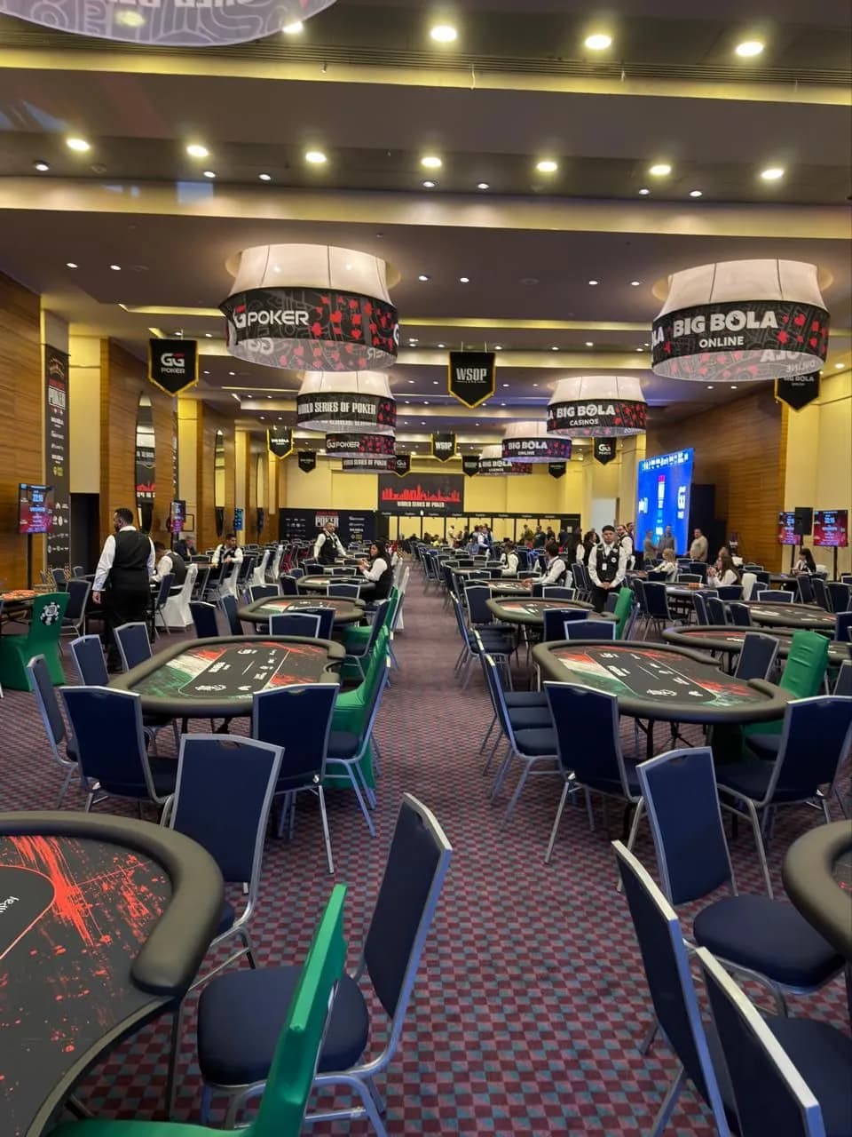 Sala de torneo llena de mesas bajo los letreros de WSOP, GGPoker y Big Bola